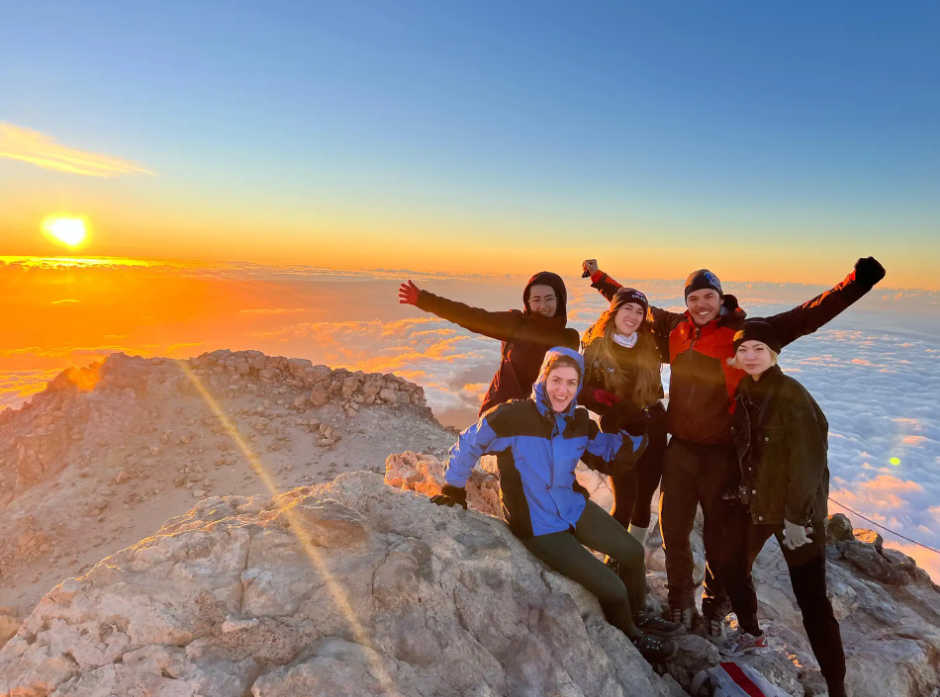 A group celebrating sunrise on Mount Teide above the sea of clouds